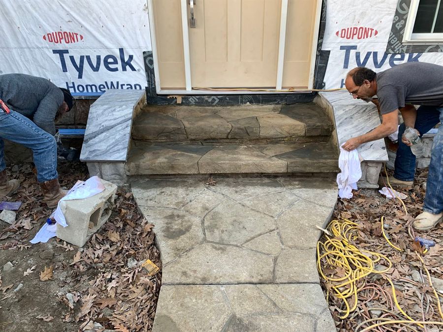 Crew finishing stamped concrete steps at a back door