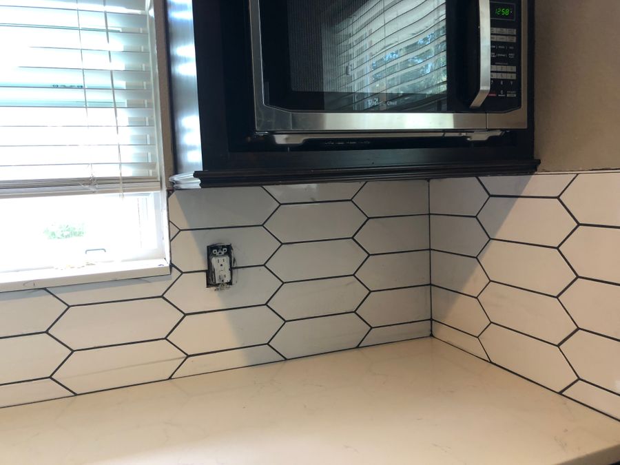 Elongated hexagon tile backsplash with dark grout lines above a kitchen counter