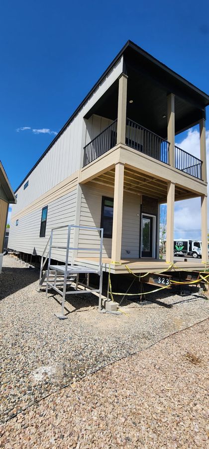 Two-story modular home with a balcony on a gravel lot