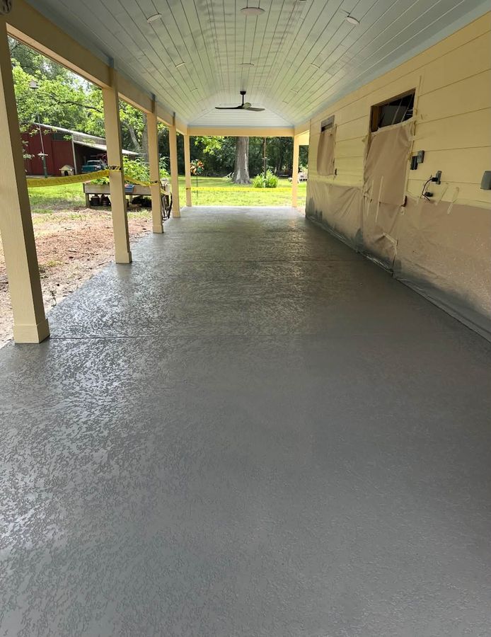 Long covered concrete slab running along a house with a yard beyond