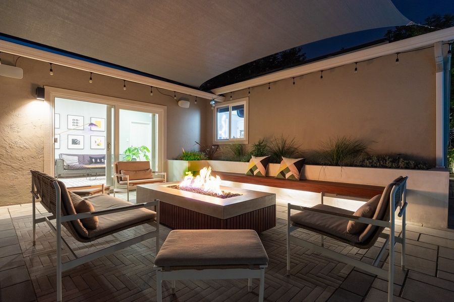 Evening view of the fire table with lit bench, string lights and warm interior glow through sliding doors