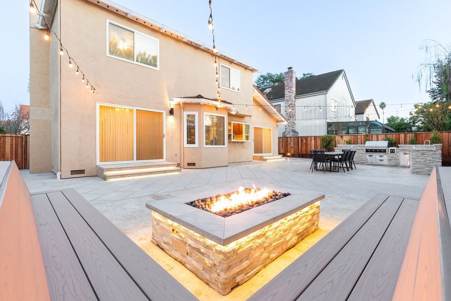 Twilight view over the L-shaped bench to the fire feature, the house and the dining area and kitchen beyond