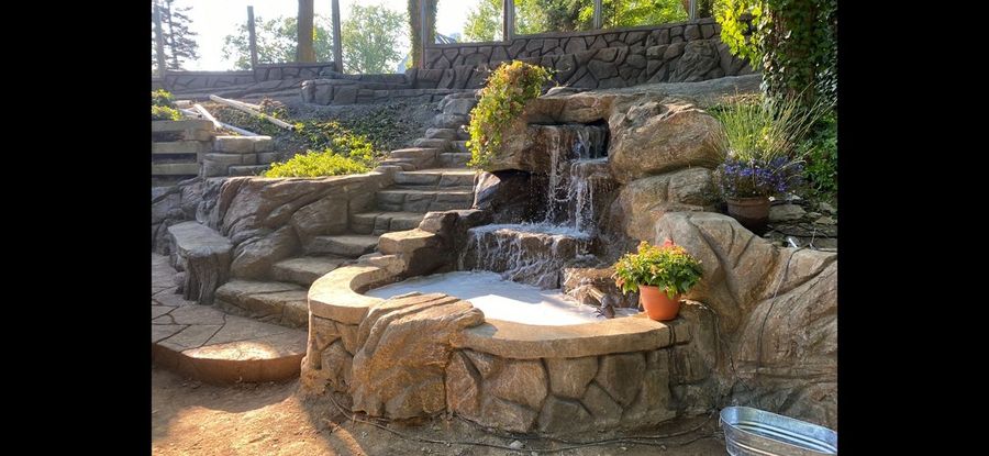 Waterfall and pool with stone-look steps and planters