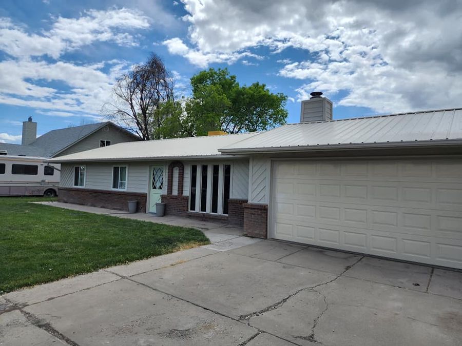 Ranch house with an attached garage, metal roof and lawn