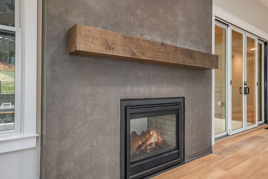 Roman clay fireplace surround in warm gray with a rustic wood mantel and gas fireplace