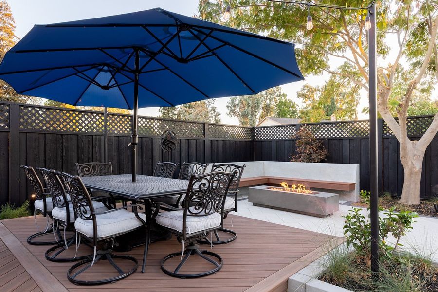Dining table with swivel chairs on a wood-look deck, with the fire table and bench behind