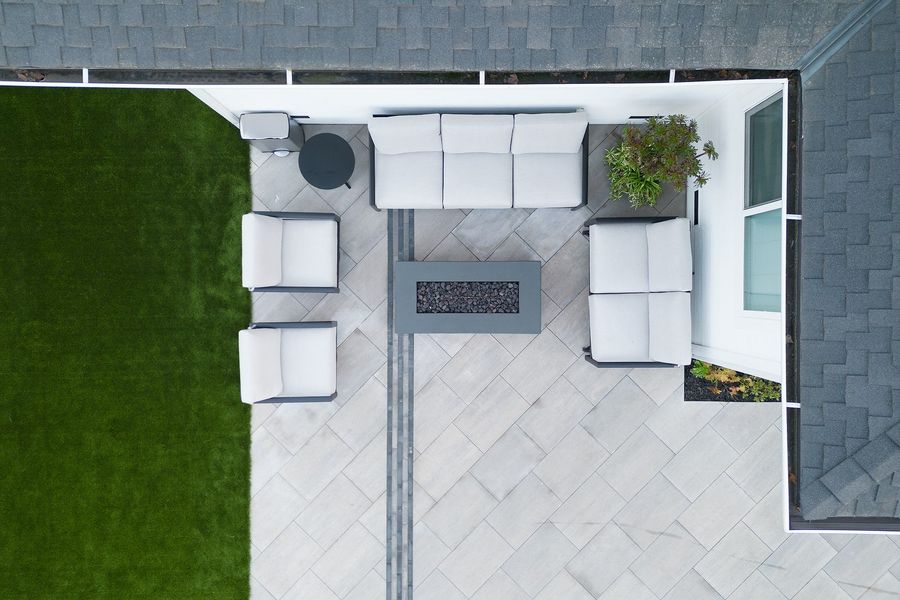 Overhead view of the lounge, a rectangular fire table with sofa and chairs on large pale slabs with a dark inset band