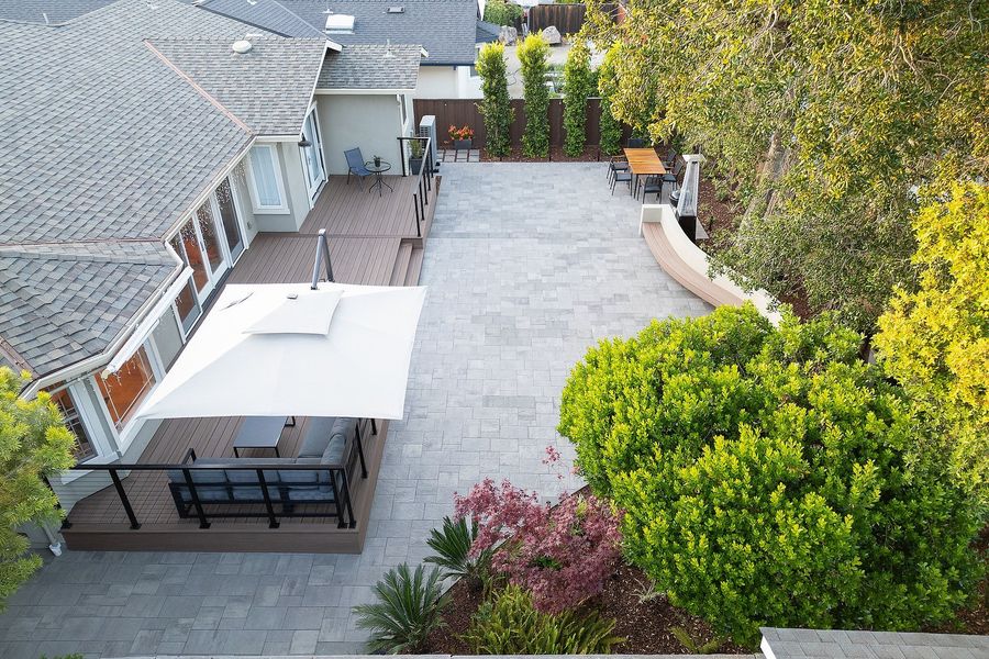 Daytime aerial of the paver terrace, wood-look deck, cantilever umbrella and planted borders