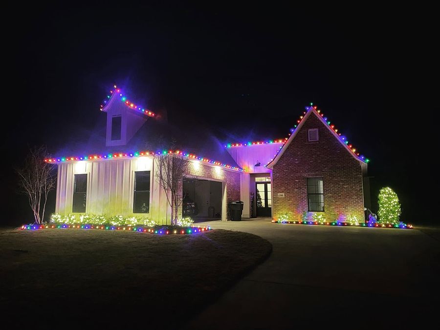 Colorful roofline lights and a lit tree on a Shreveport home