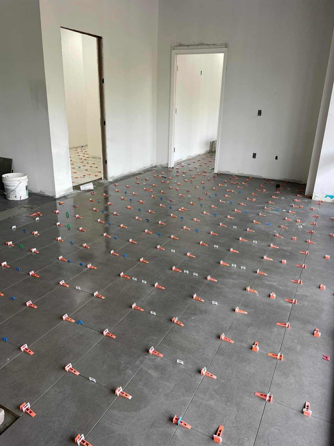 Large-format dark gray floor tile with leveling clips in an empty room