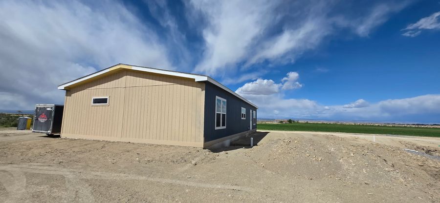 Tan and charcoal modular home exterior under a big sky