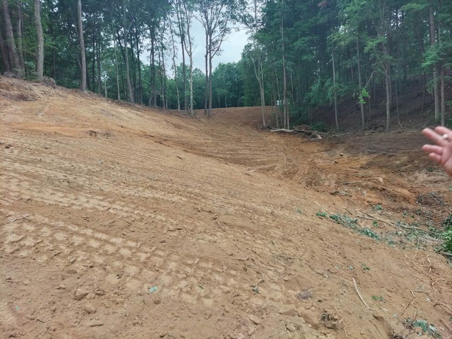 Cleared hillside of bare soil with dozer tracks after land clearing