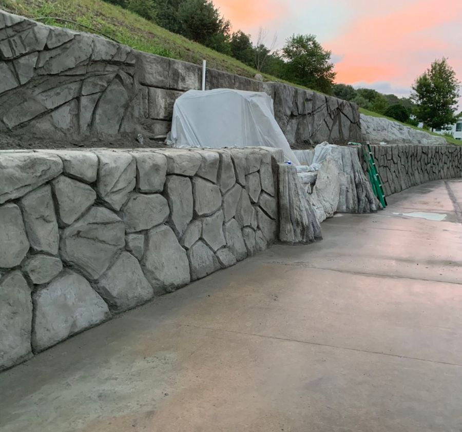 Stone-look retaining walls beside a poured concrete drive
