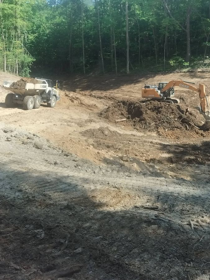 Articulated dump truck and excavator working a cut in the woods