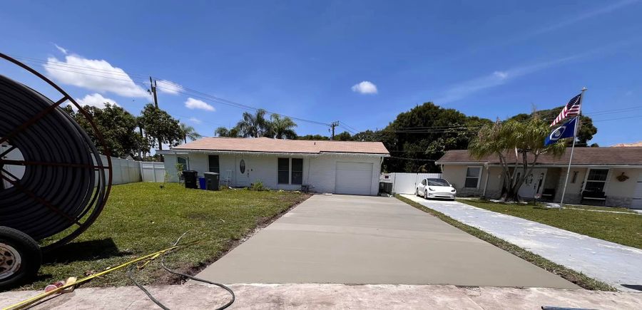 Long concrete driveway leading toward a Florida home