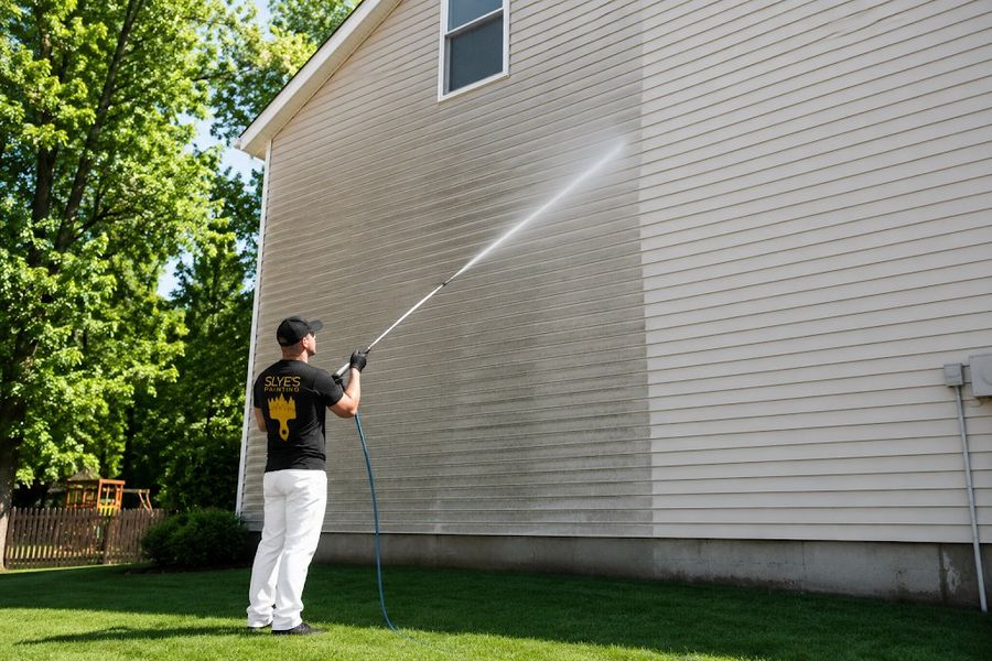Slye&rsquo;s Painting crew member pressure washing house siding