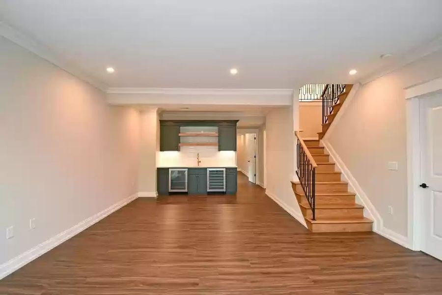 Finished basement with freshly painted walls, crisp white trim and a stairwell