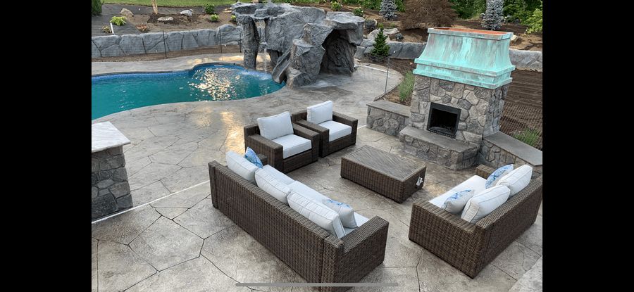 Pool patio with a rock waterfall, outdoor fireplace and seating