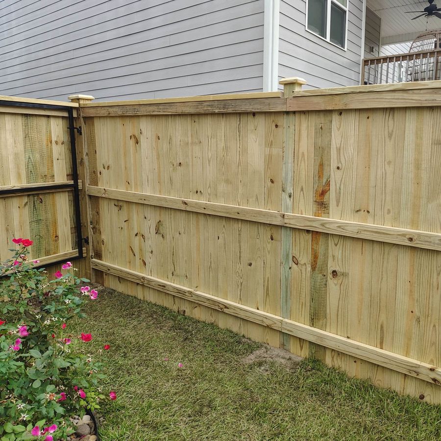 Wood privacy fence corner with roses along the bed