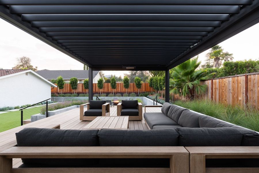 Low view from the sofa under the pergola across the deck to the lawn, ornamental grasses and the house