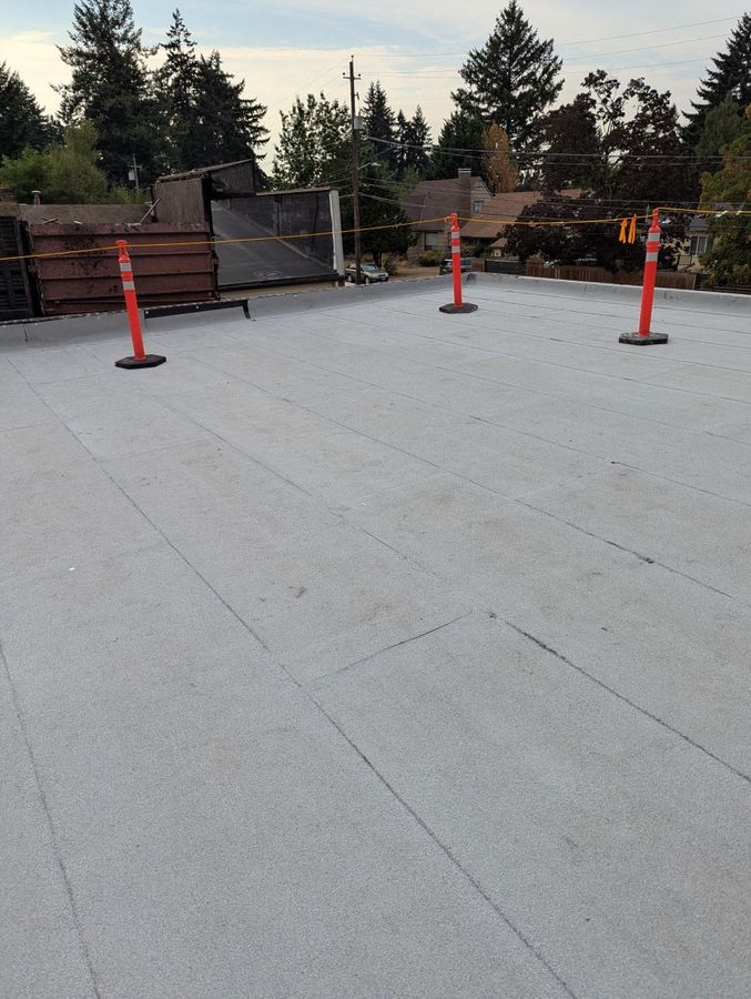 Grey built-up roof field with orange cones set out along the edge