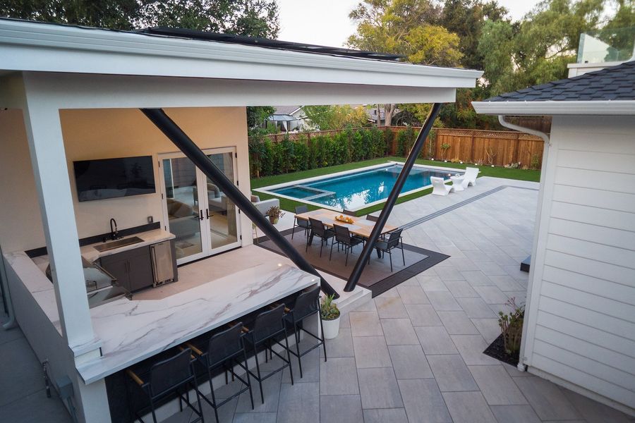 Aerial view over the cabana bar and strut to the dining table and the large pale paving, with succulents along the house wall