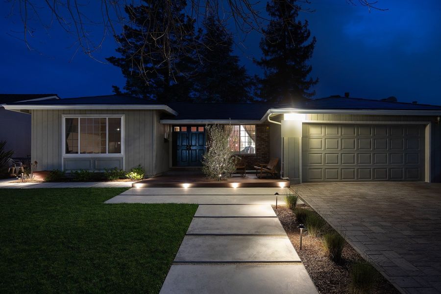 Front walkway at night with concrete pavers, path lights, lights set into the deck edge and a warmly lit entry