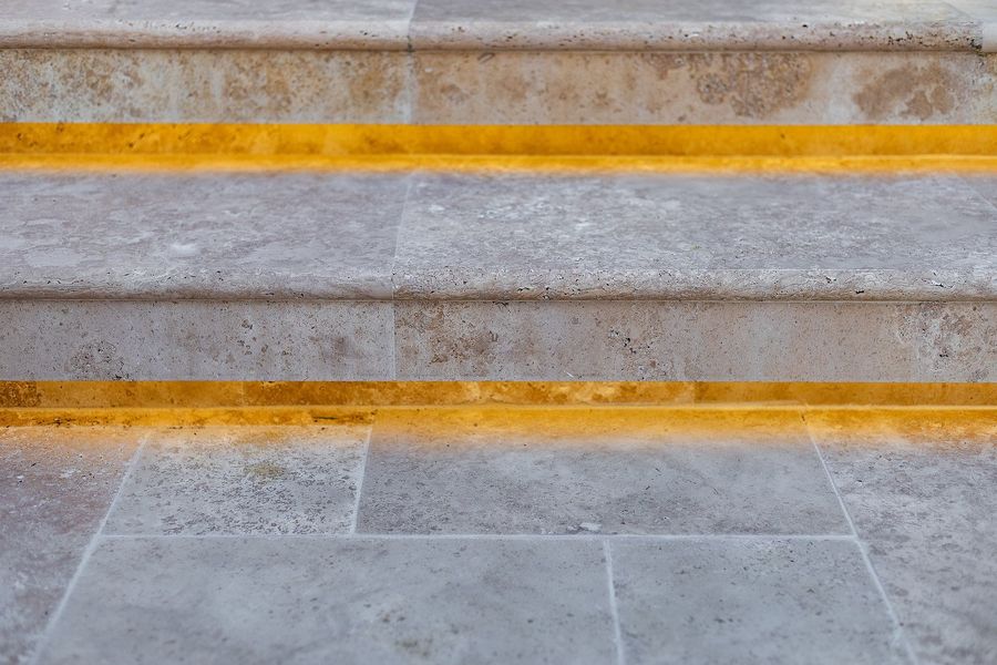 Close view of pale stone steps with two thin lines of warm light along the risers
