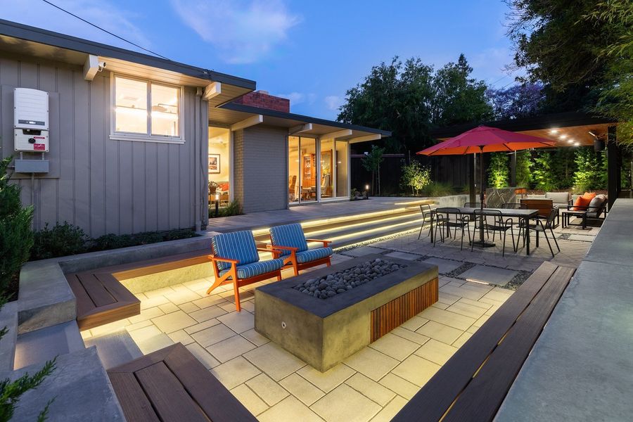 Sunken paver lounge with built-in benches lit from below, a fire table and the pavilion in the distance