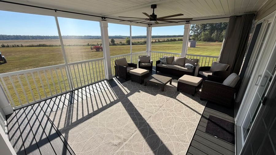 Inside a new screened porch with patio furniture looking out over a field