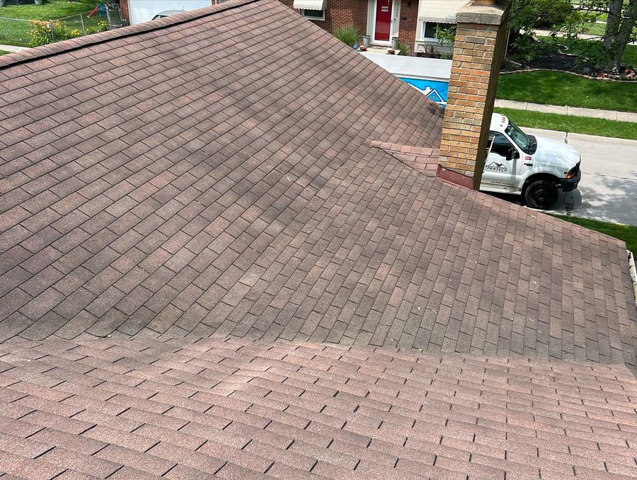 A large asphalt shingle roof part way through a ProTech soft wash