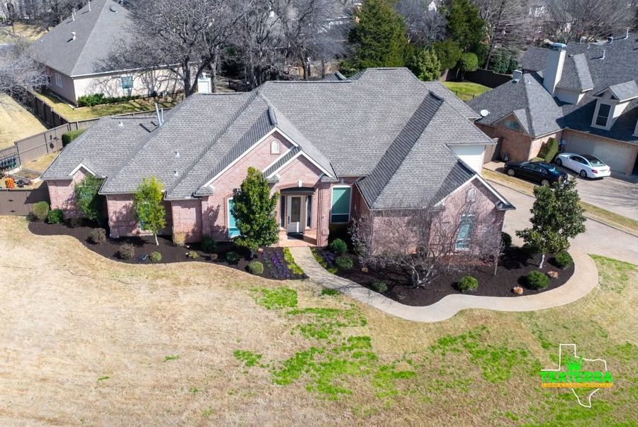 Aerial view of a brick home with new curved landscape beds