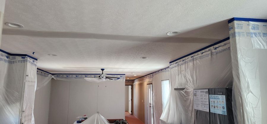 Long interior room masked off with plastic sheeting and ready for spray painting