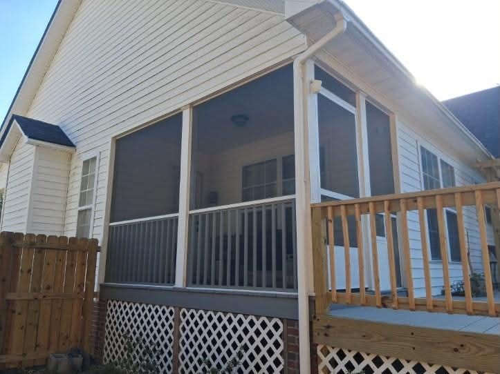 Screened porch beside a wood deck with lattice skirting