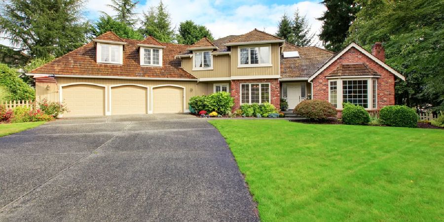 New asphalt driveway leading to a large brick home