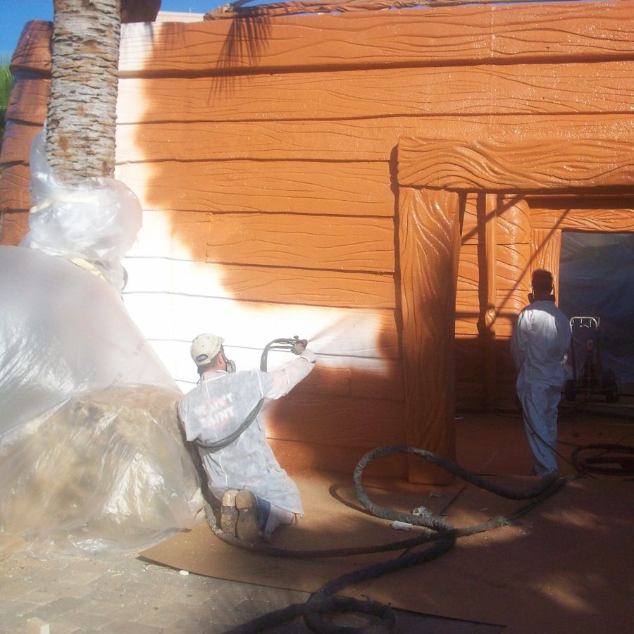 Hotspray crew in protective suits spray applying an industrial coating to a building exterior