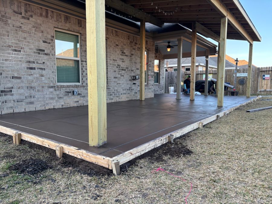 Wide view of a covered back porch slab with wood forms and a crew at work