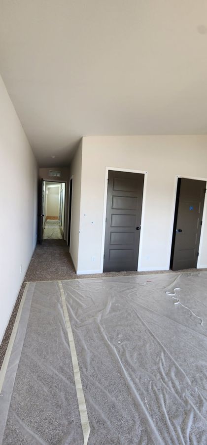 Hallway with new drywall, dark doors and floor protection laid down during finishing