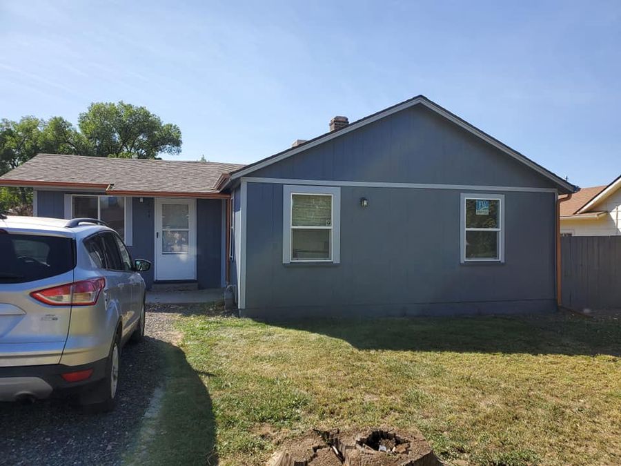 Blue-grey stucco ranch house with a green lawn in the Grand Valley