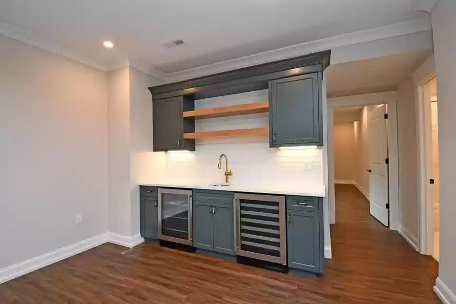 Painted charcoal cabinets with a floating wood shelf in a finished wet bar