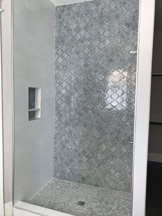 Patterned gray tile shower wall with a recessed niche