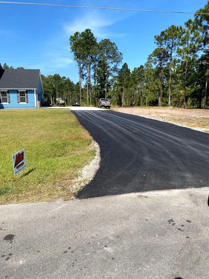 Smooth jet black driveway curve beside a blue house