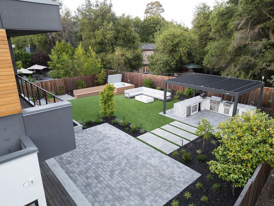 Aerial view of the grey paver terrace and concrete stepping pads crossing the lawn toward the pergola and fire seating