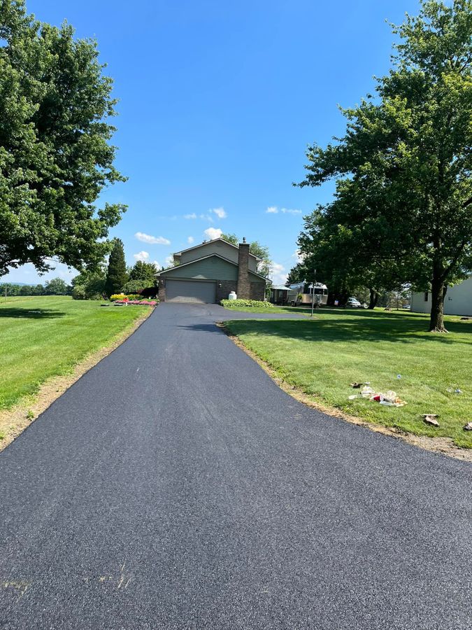 Long newly paved private driveway with clean edges and tall trees