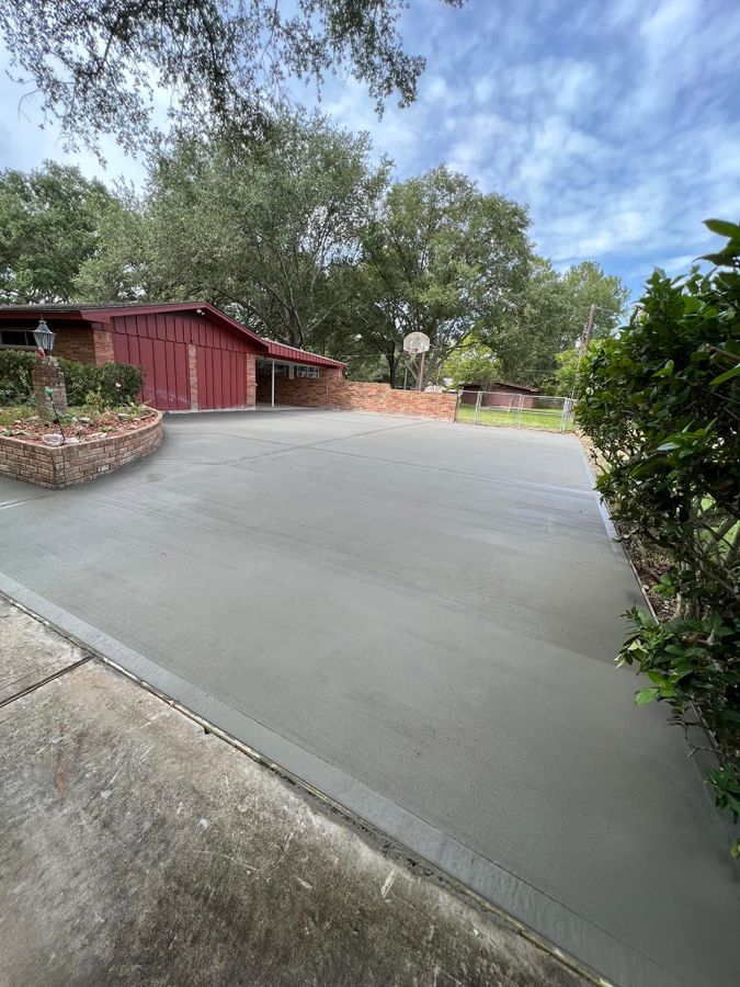 Wide concrete driveway curving past a red building