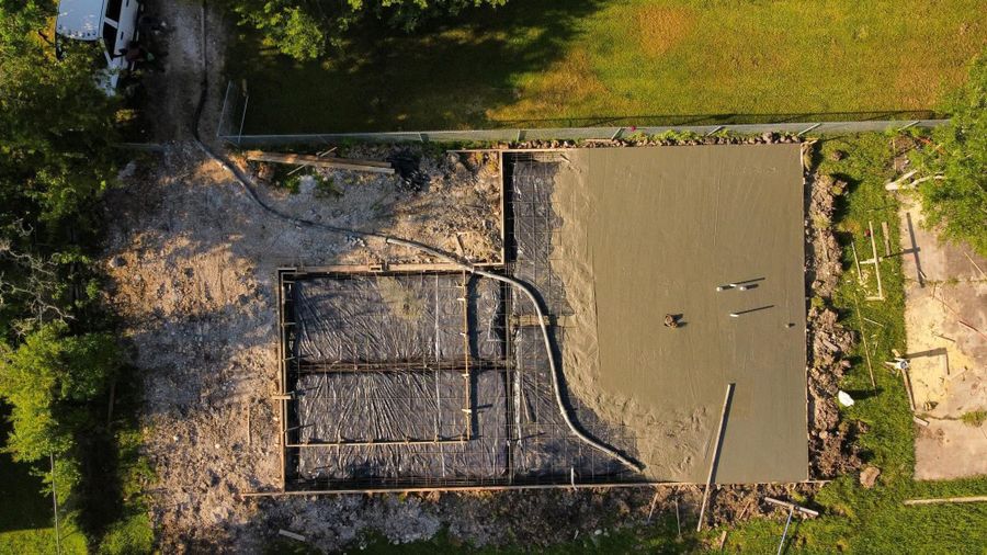 Overhead view of wet concrete being placed in a formed slab with steel still showing in the unpoured section