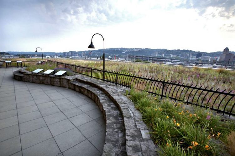 Garden roof terrace with a curved stone wall and lamp posts above the Portland hills